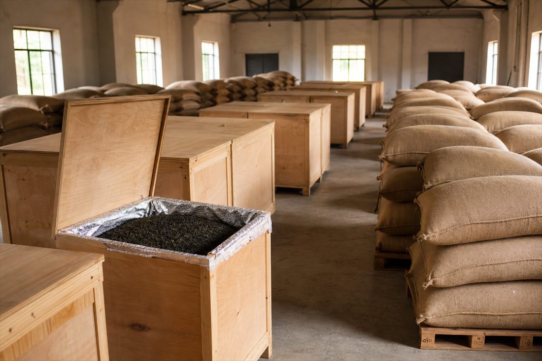 Tea chests and jute sacks of tea stacked on pallets inside a warehouse